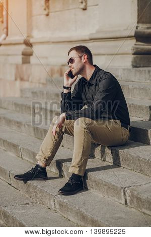 A guy in a nice town, walking, listening to music and taking pictures themselves on the phone
