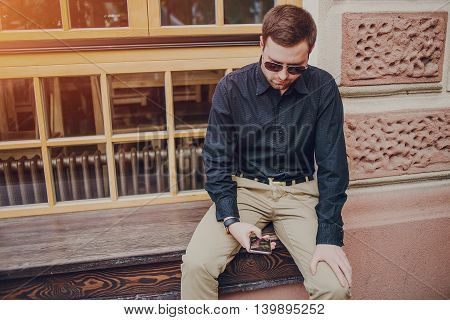 A guy in a nice town, walking, listening to music and taking pictures themselves on the phone