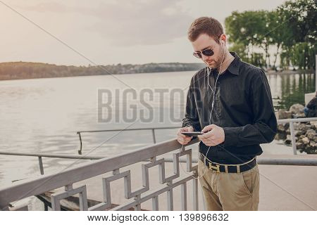 A guy in a nice town, walking, listening to music and taking pictures themselves on the phone
