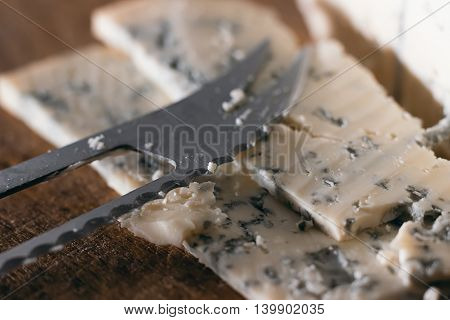 Blue cheese close up on an old wooden board and a knife
Selective focus and shallow Depth of field