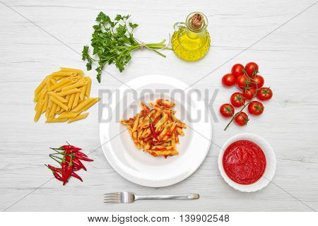 dish with penne and arrabbiata sauce on white wood