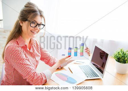 Portrait of young businesswoman showing diagrama of company's growth