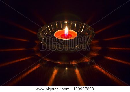 burning candle in a saucer on a wooden table
