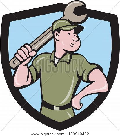 Illustration of a mechanic wielding holding spanner wrench looking to the side with one hand on hips viewed from front set inside shield crest on isolated background done in cartoon style.