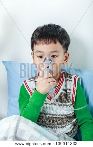 Asian Child Holds A Mask Vapor Inhaler For Treatment Of Asthma. Breathing Through A Steam Nebulizer.