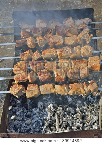 A close up of the cooking shashlik on skewers.