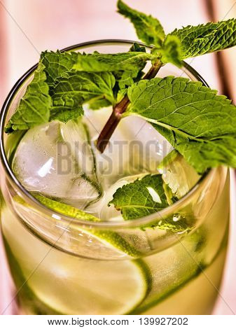 Alcohol drink. On wooden boards top of glass with alcohol drink and ice cubes. A drink number two hundred fifty seven cocktail mohito with slice lime and mint leaf. Country life.