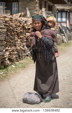 Pisang village, Nepal - May 5, 2016: Portrait of an unidentified tibetan woman with a baby in the Himalayas mountains in Lower Pisang village, Nepal. Annapurna Circuit Trek