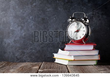 Alarm clock on notepads in front of chalk boad. Back to school concept with copy space
