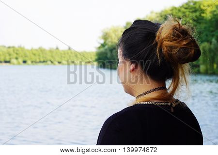 back or rear view of young woman looking over lake