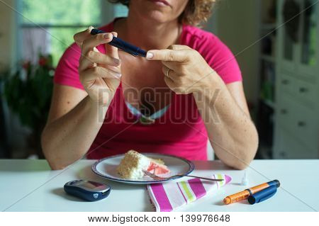 Close up of a woman using lancelet on finger to take sample of blood sugar.