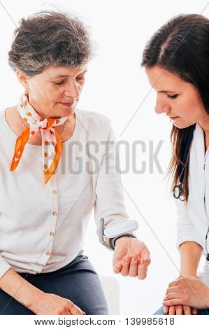 Young doctor is examining patient with tensiometer - isolated on white
