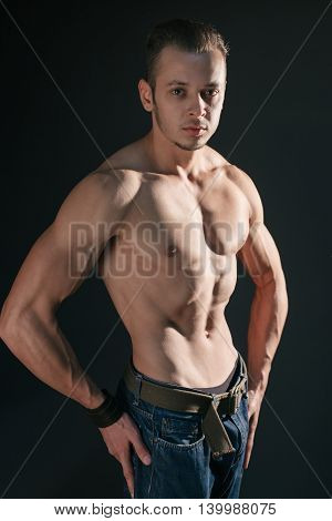 Shirtless serious man with well defined muscles posing at studio
