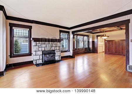 Empty Family Room With Antique Stone Fireplace And Hardwood Floor.