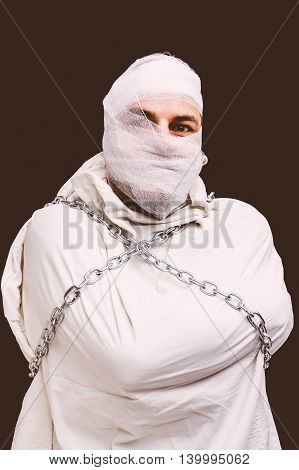 Bandaged patient in straitjacket and chains sepia version