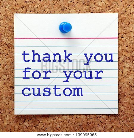 The words Thank You For Your Custom in blue text on a note card pinned to a cork notice board as a reminder of good customer service