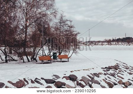 Finland Helsinki, Two Benches And A Waste Bin At The Shore Of Island Of Tervasaari On A Winter Day