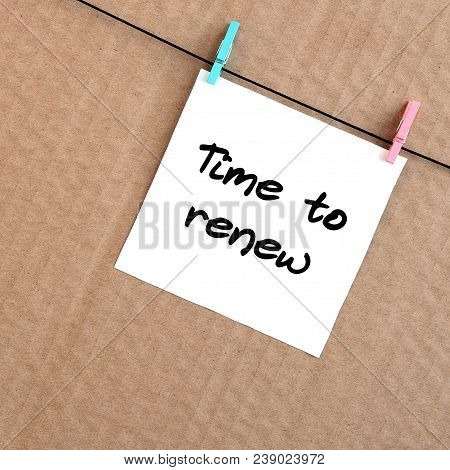 Time To Renew. Note Is Written On A White Sticker That Hangs With A Clothespin On A Rope On A Backgr