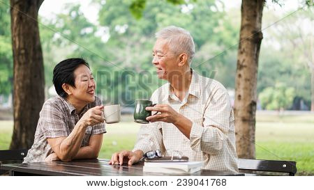 Asian Senior Couple Relax Drinking Coffee In Summer Park, Green Nature