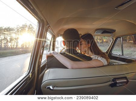 Young Wedding Couple Sitting Smiling Inside Retro Car. Just Married Embrace Is Hugging Inside Car. B