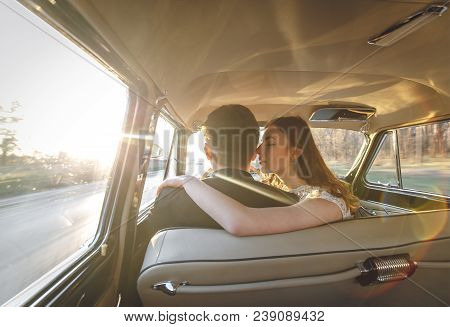 Young Wedding Couple Sitting Smiling Inside Retro Car. Just Married Embrace Is Hugging Inside Car. B