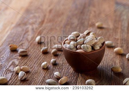 Overturned Ceramic Bowl With Pistachios On Wooden Background, Top View, Selective Focus. Some Copy S