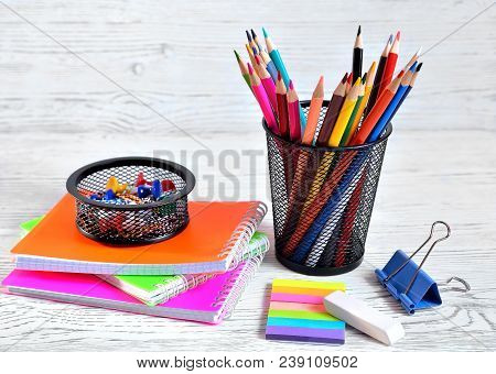 Color Pads And Colored Pencils In A Container, Eraser And Paper Clip On An Aged White Background