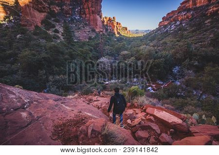 Male Hiker Descending A Steep And Rugged Red Rock Tail From A Scenic Overlook Of Fay Canyon, Coconin