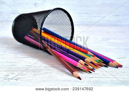Many Multi-colored Pencils In A Mesh Glass On A Light Natural Non-uniform Background