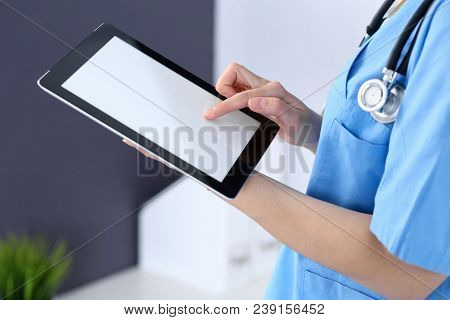 Woman Doctor Using Tablet Computer While Standing Straight In Hospital Office, Closeup. Healthcare, 