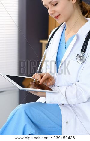 Woman Doctor Using White Tablet Computer While Working In Hospital.