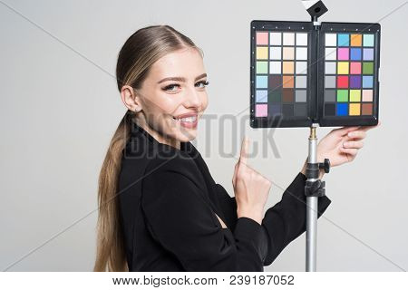 Young Photographer Pointing At Color Checker Card, While Working In Studio. Girl In Formal Suit Prep