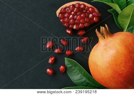 Sweet And Juicy Indian Pomegranate On Black Granite Table. Ripe Red Pomegranate In Top View Flat Lay