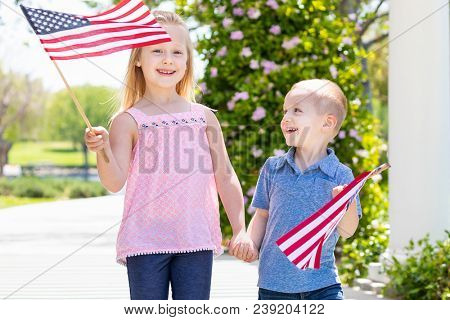 Young Sister and Brother Waving American Flags At The Park.