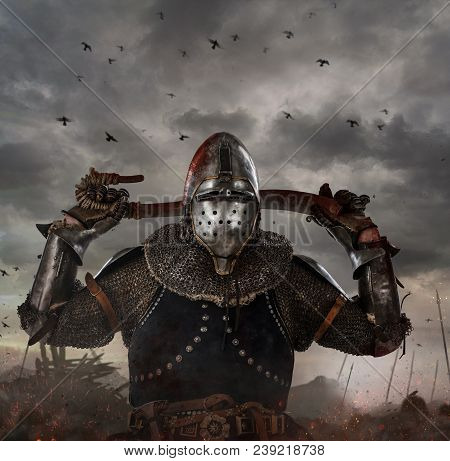 Knight With Sword In Battlefield With Dark Clouds On Background.
