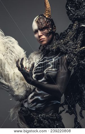Portrait Of Devil Woman In Black And White Clothes With One Horn On Her Head. Isolated On Grey Backg