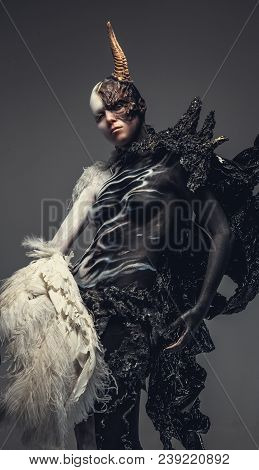 Portrait Of Devil Woman In Black And White Clothes With One Horn On Her Head. Isolated On Grey Backg