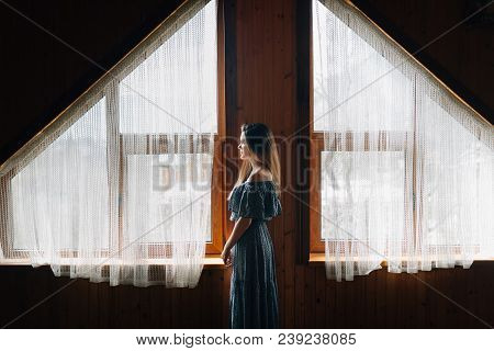 A Cozy Wooden House With Large Windows And Light Curtains