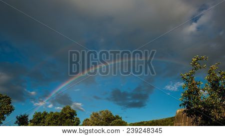 Rainbow At The Background Rain Clouds. Spring Season In The Village. Panorama Sky In The Sunny Day.