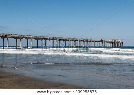 People Surf Near A Concrete Research Pier At La Jolla Shores In San Diego, California.