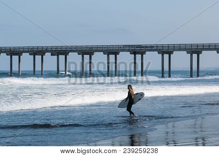 La Jolla, California/usa - April 28, 2018:  A Lone Female Surfer Carries A Surfboard Out To Sea Near