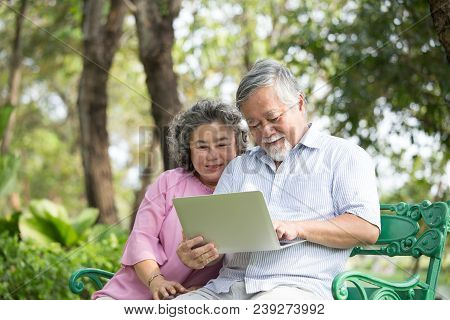 Senior People Using Laptop For Live Chat With Friend At Outdoor Park. Elder People Using Laptop With