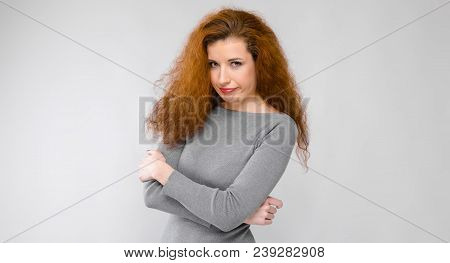 Charming Young Girl With Red Hair. A Young Girl In A Gray Sweater. Young Girl On A Gray Background.