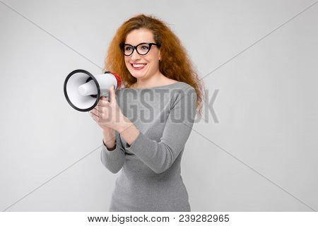 Charming Young Girl With Red Hair. A Young Girl In A Gray Sweater. Young Girl On A Gray Background.