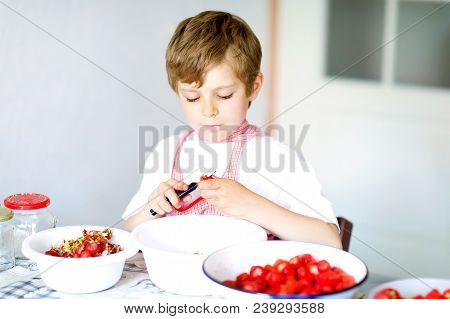 Little Blond Kid Boy Helping And Making Strawberry Jam In Summer. Funny Child Cleaning Berries And P