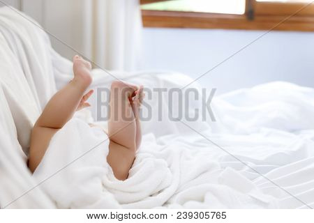Cute Little Baby Playing With Own Feet After Taking Bath. Adorable Beautiful Girl Wrapped In White T