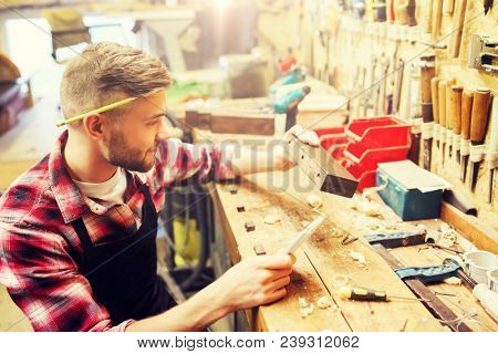 profession, carpentry, woodwork and people concept - carpenter working with wood plank at workshop