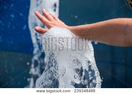Hand Touch The Fountain. A Stream Of Water From The Fountain Is Touched By Hand.