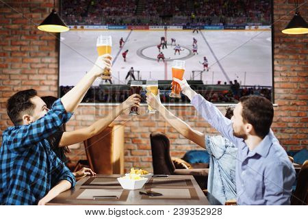 Group Of Young Men Cheering On Their Favorite Hockey Team Watching The Game On Tv At The Local Pub H