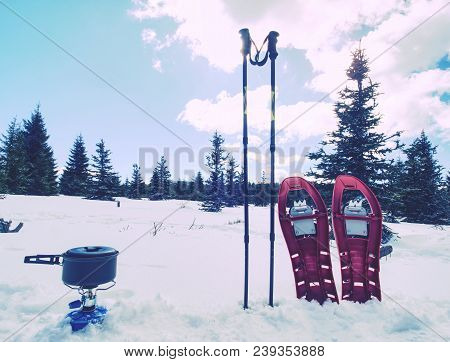Lunch Time During Winter Trail. Camping On Snow And Cooking. Red Snowshoes And Trekking Poles Stand 